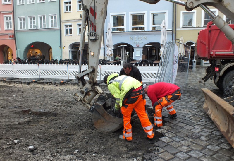 Der Bagger schaufelt den Haufen weg - Arbeiter klauben die restlichen Steine zusammen