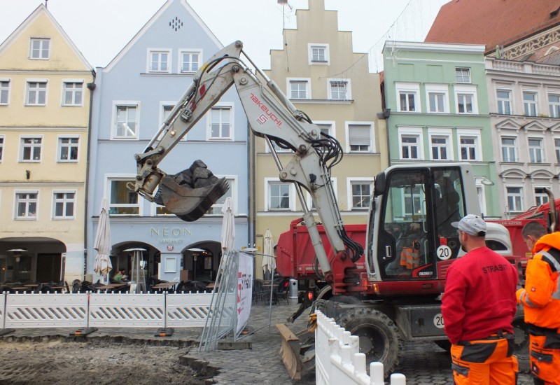 Der Bagger schaufelt den Haufen weg - Arbeiter klauben die restlichen Steine zusammen