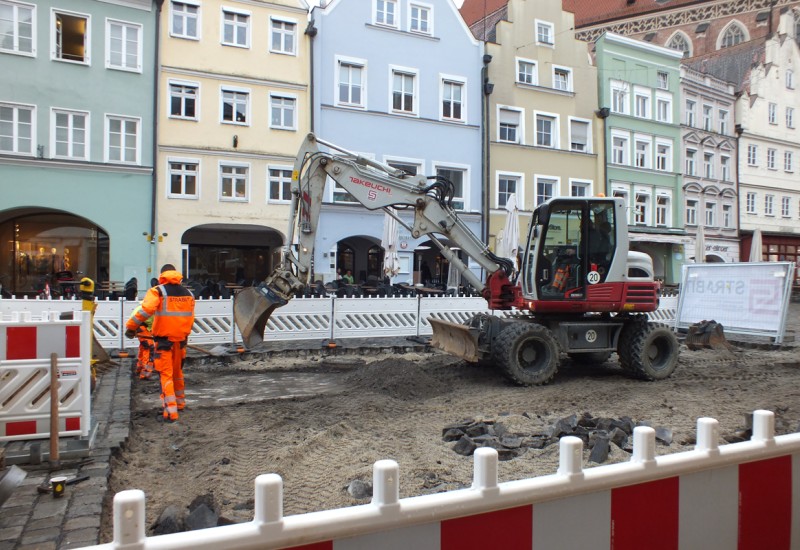 Die Arbeiter bereiten eine ebene Kiesschicht für den provisorischen Asphaltbelag vor